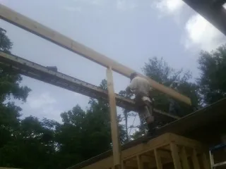 Carpenter setting a ridge beam over a new addition frame — Ice Dam Removal by Roofing Brothers in Kensett