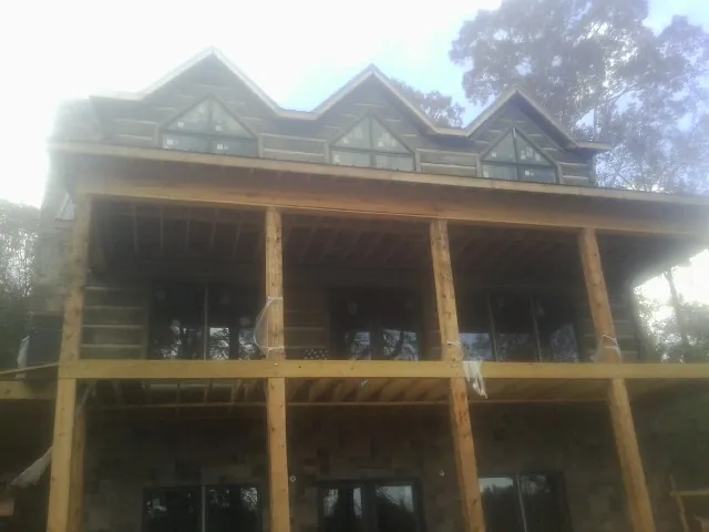 Dormers and porch framing on a large log home under construction — Roof Coating work by our crew in Kensett
