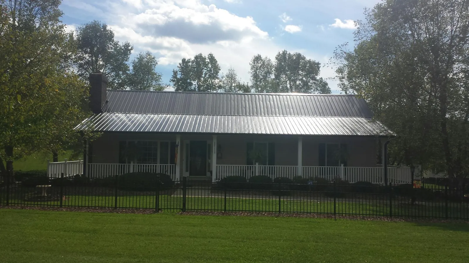 Gray metal roof on a brick ranch with a full width front porch — Gutter Guard Installation work by our crew in Kensett