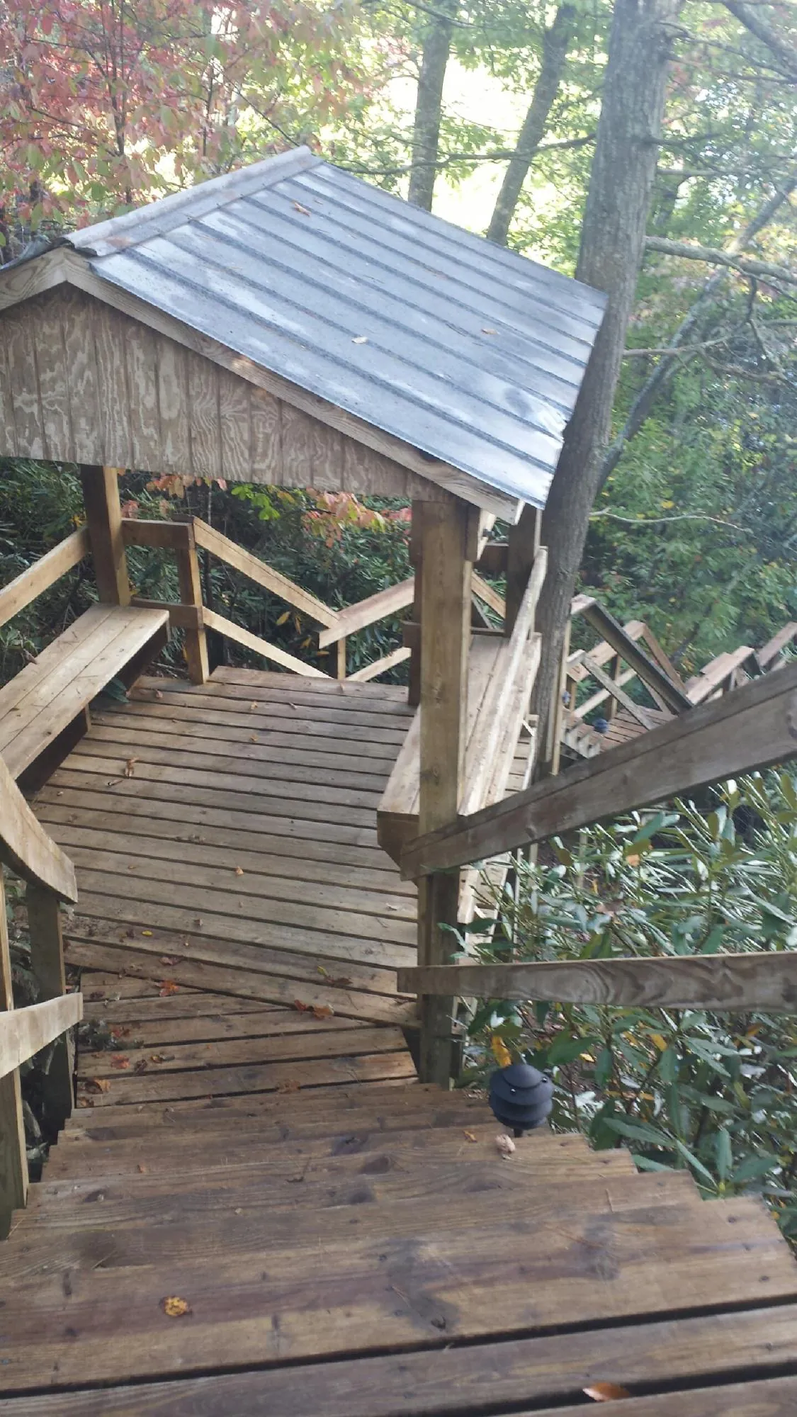 Metal roofed shelter over wooden steps on a wooded walkway — Skylight Repair & Installation work by our crew in Kensett