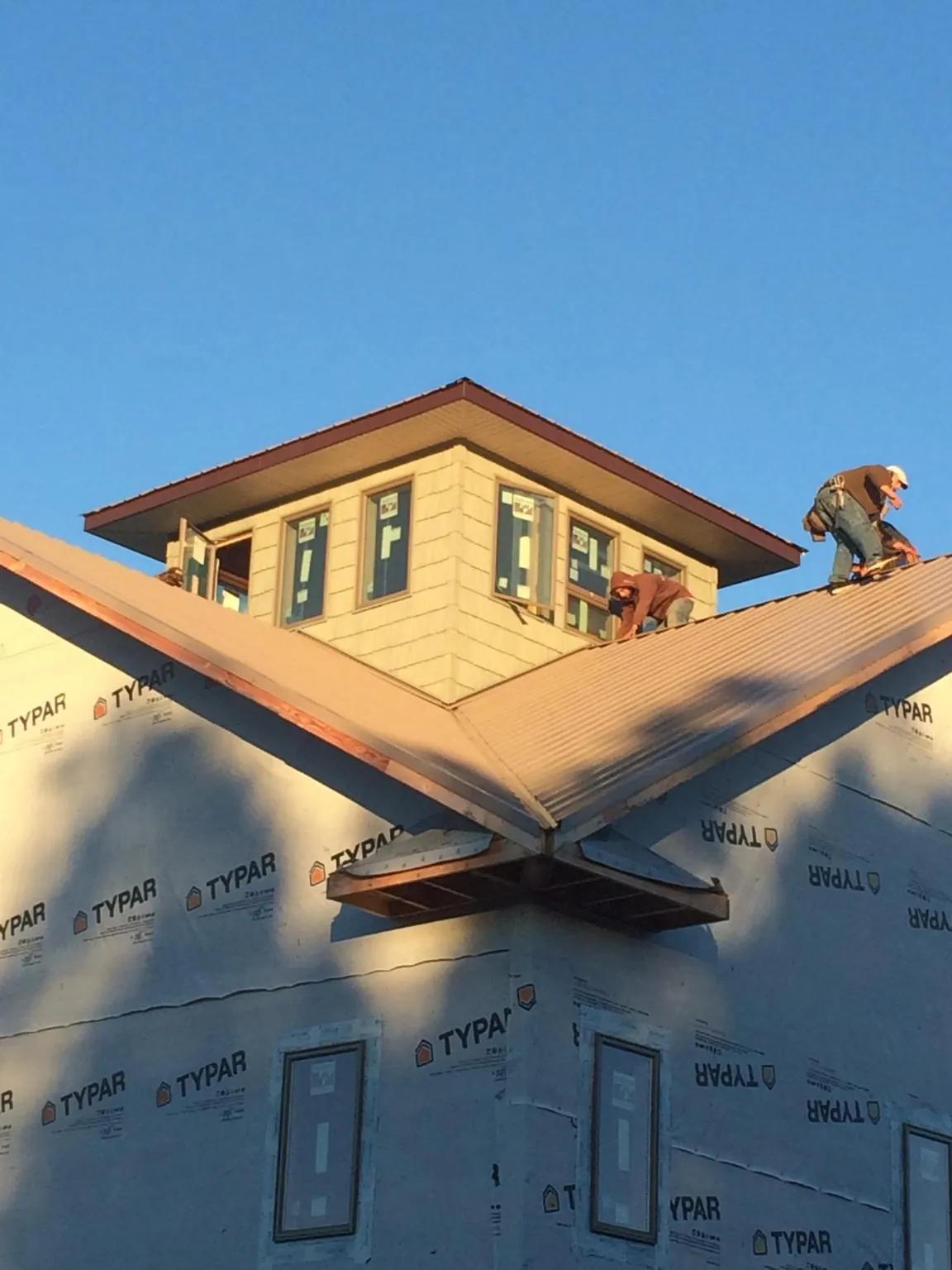 Roofers working around a rooftop cupola on a new metal roof at sunset — Roof Waterproofing in Kensett by Roofing Brothers
